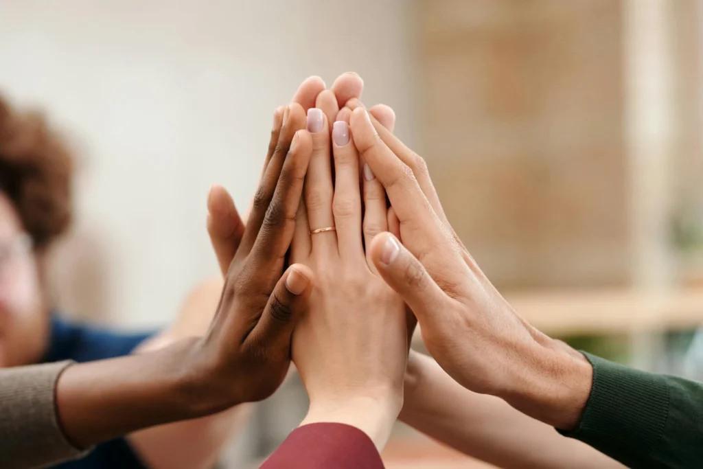 Nell'immagine si vedono le mani di cinque persone che si battono il cinque.